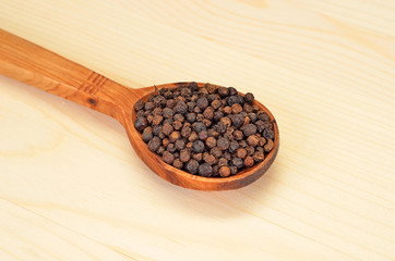 Black pepper granules in wooden spoon