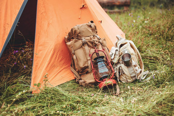 the tent and two backpacks near a tourist track in mountains on green grass