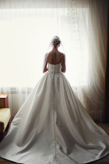 A view from behind on a stunning bride standing at the window