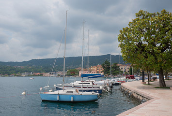 Fototapeta na wymiar Uferpromenade Salo am Gardasee, mit Segelbooten und Magnolienbä