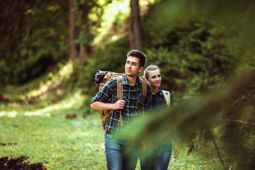 A couple hikers Hiking with backpacks walk along a beautiful mountain area. The concept of active rest