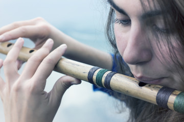 Musician playing a wooden flute on the banks of the river © afanasyeva_t