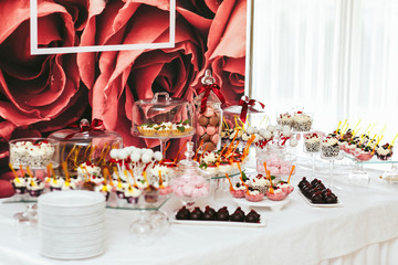 Pastry, sweets and choclates stand on a table covered with white