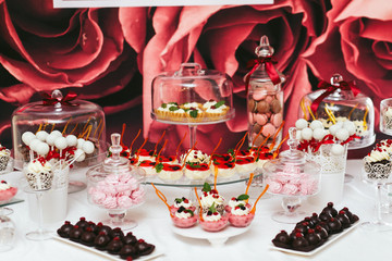 Pink, white and brown chocolates stand on glass dishes on a buff