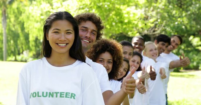 Volunteers standing in a row giving thumbs up to camera