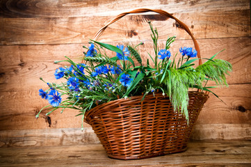 Cornflowers in basket on wooden background