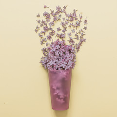 Flat lay set: Lilac flowers poured from a glass on pastel background. Top view.