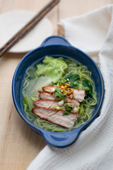 Green noodles in soup with red sliced pork