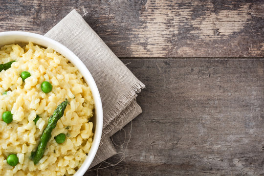 Risotto with asparagus, parsley and peas in a bowl on a rustic wooden table


