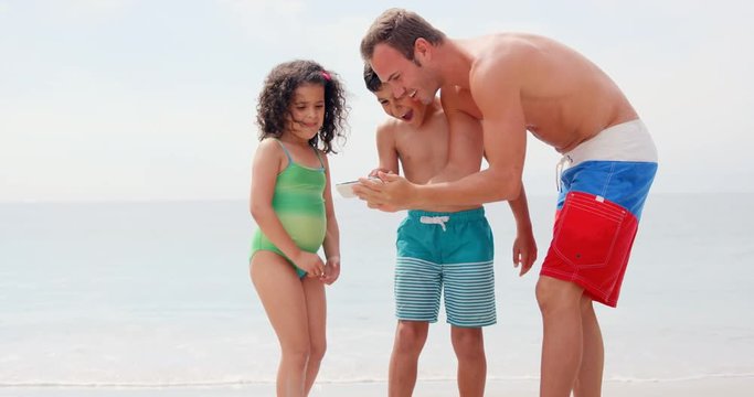 Father showing pictures to children on the beach