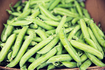 close up of green peas in box at street market