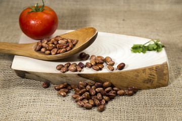 Organic red dried beans over wooden tray and sackcloth, studio image