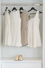 earth tone color dress hanging on rail in white wardrobe