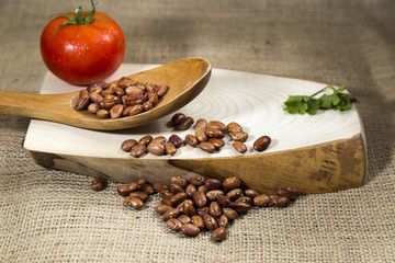 Organic red dried beans over wooden tray and sackcloth, studio image