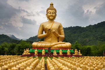 Naklejki  Złote posągi Buddy, góry, tło, pada mgła