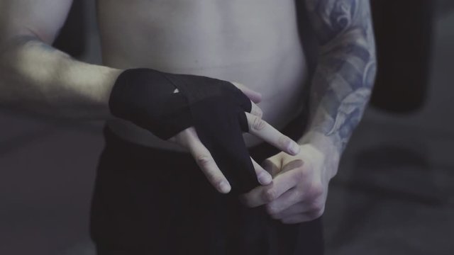 Fighting preparation, tattooed fighter wrapping his hands