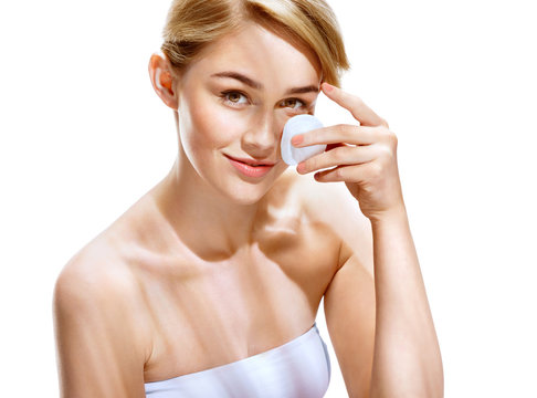 Happy woman cleaning her face with cotton pads over white background. Youth and Skin Care Concept.