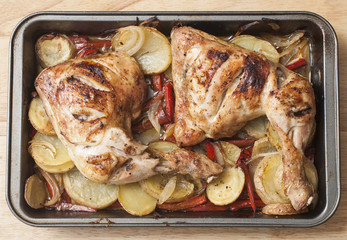 Roasted chicken legs with potatoes, onions and peppers.