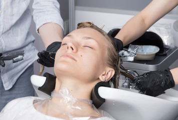 Obraz na płótnie Canvas Beautiful blonde female client coloring hair in hairdressing salon