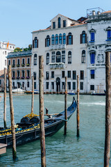 Fototapeta na wymiar Travel photo: view on Grand Canal, gondola berthed between piles and ancient historical houses in Venice, Italy, popular touristic place