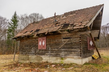 Old rural abandoned wooden collapsing house agains cloudy sky in autumn season