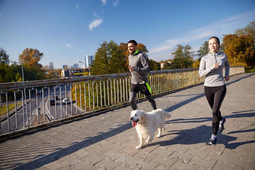 happy couple with dog running outdoors