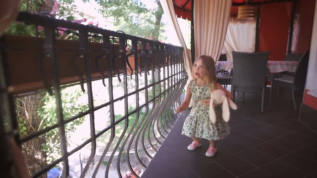 Happy blonde girl in the dress having fun dancing at a bright balcony