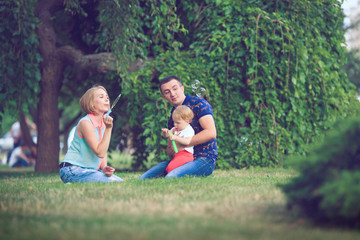 Happy family of three lying in the grass . Warm effect added.