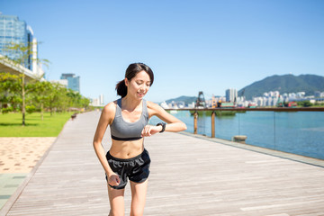 Woman running in a city and checking on smart watch