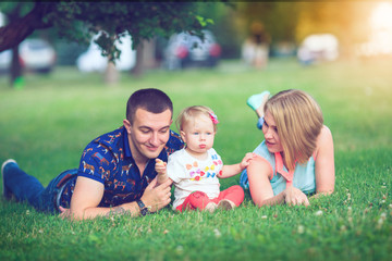 Happy family of three lying in the grass . Warm effect added.