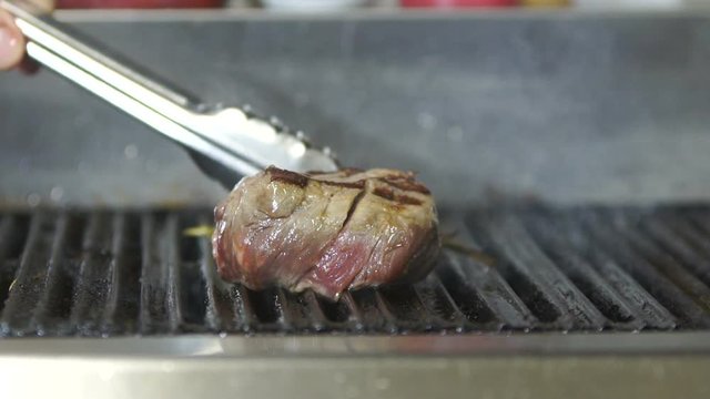 Beef steak is grilling at restaurant kitchen. Slow motion