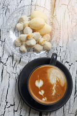 Coffee cup of cappuccino and Thai cookie with reflection from windown
