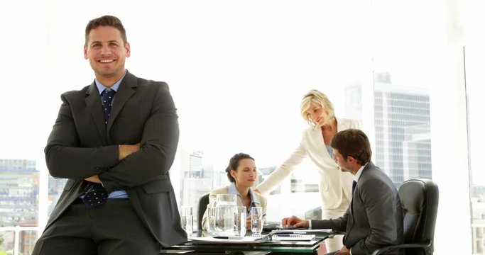 Businessman leaning on desk with team behind him