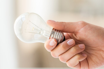 close up of hand holding edison lamp or lightbulb