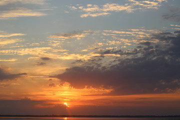 Beautiful colourful orange sunset over a calm lake. Reflection of clouds in water