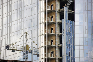 Fototapeta na wymiar Reflection of a construction site in windows of modern office building