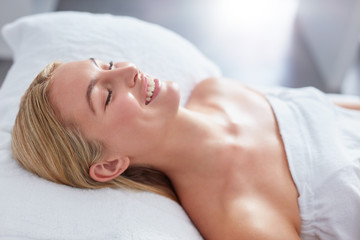Fototapeta na wymiar Smiling woman in a day spa relaxing on massage table