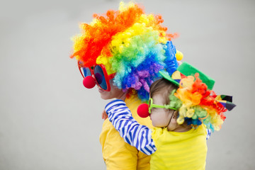 Young woman and her adorable little daughter in clown costume outdoors at summer day