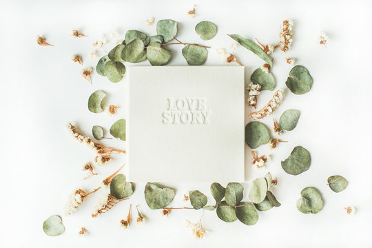 white wedding or family photo album with words "love story", frame with dry and fresh branches isolated on white background. flat lay, overhead view