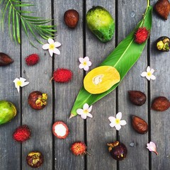 Indonesian fruits: mango, rambutan, snake fruit, mangosteen at grey wooden background. Flat lay. 