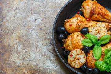 Grilled chicken legs with garlic,  basil, olives and spices in a cast iron skillet.Top view. Copy space