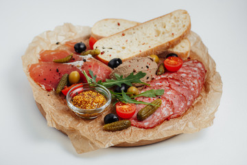 bread with meat, sausage, gherkins, tomatoes and mustard on a wooden tray