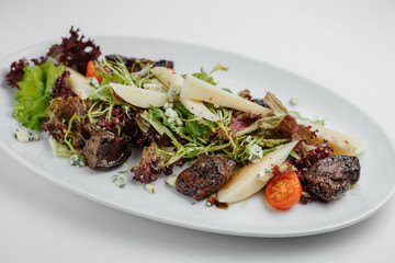 grilled meat with lettuce and greens with tomatoes on a white plate