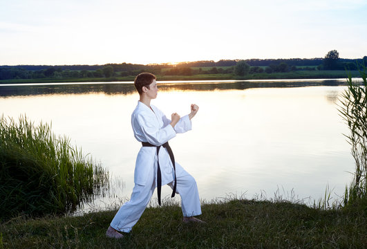 Girl in white kimono in rack karate on the background of the river