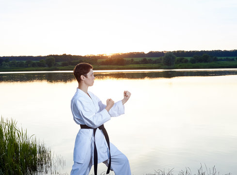 A young girl stands in the rack karate on the background of the river