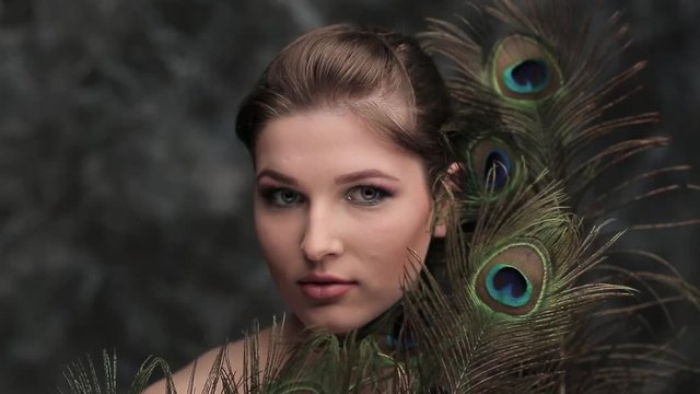 girl with colored makeup and peacock feather