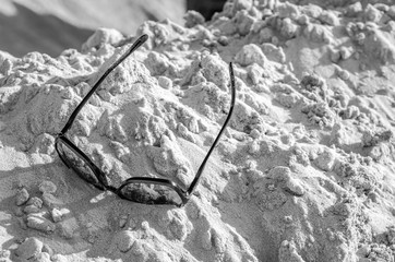 The black sunglasses lying on a sandy sea beach