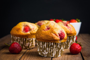Homemade muffins with strawberries on the wooden background