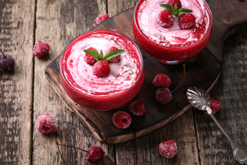 Pink raspberry smoothie with ice cream and mint on a rustic wood background