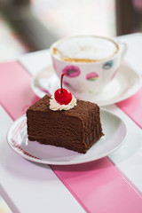 Close - up chocolate cake on a wooden table in pastel tone.Chocolate cake decorated with cherries